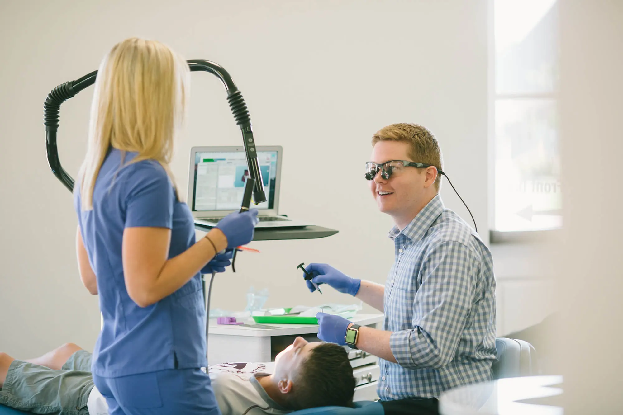 A Pediatric Dentist show prepare begin dental treatment to young boy patient in dental chair at Pediatric Dentistry and Orthodontics of Forsyth - Cumming in Cumming, GA.
