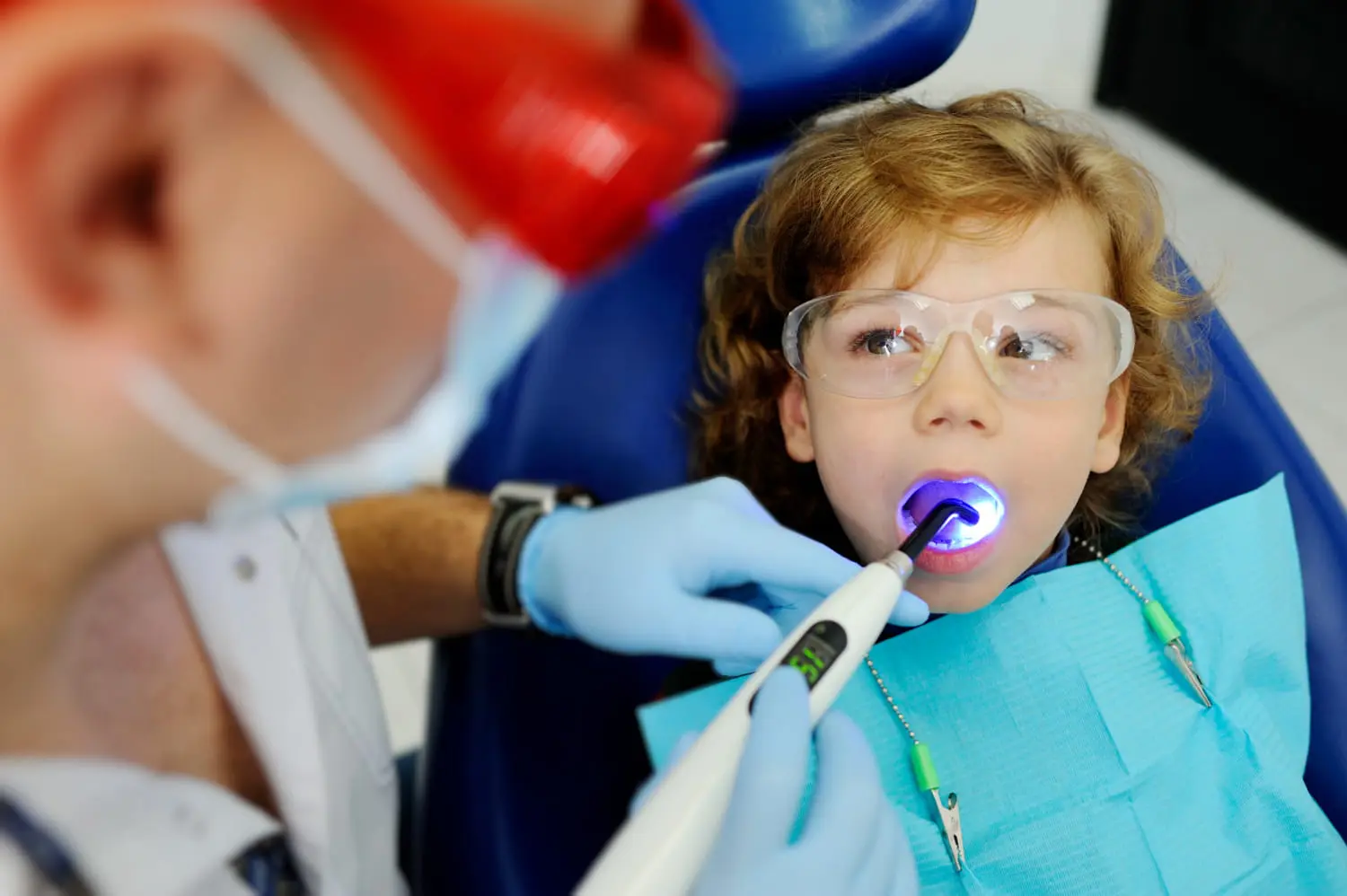 At Pediatric Dentistry and Orthodontics of Forsyth - Cumming in Cumming, GA. A child undergoes a gentle dental Laser Dentistry procedure with a curing light tool, illustrating how early cavity detection enables smaller fillings and less invasive treatments.