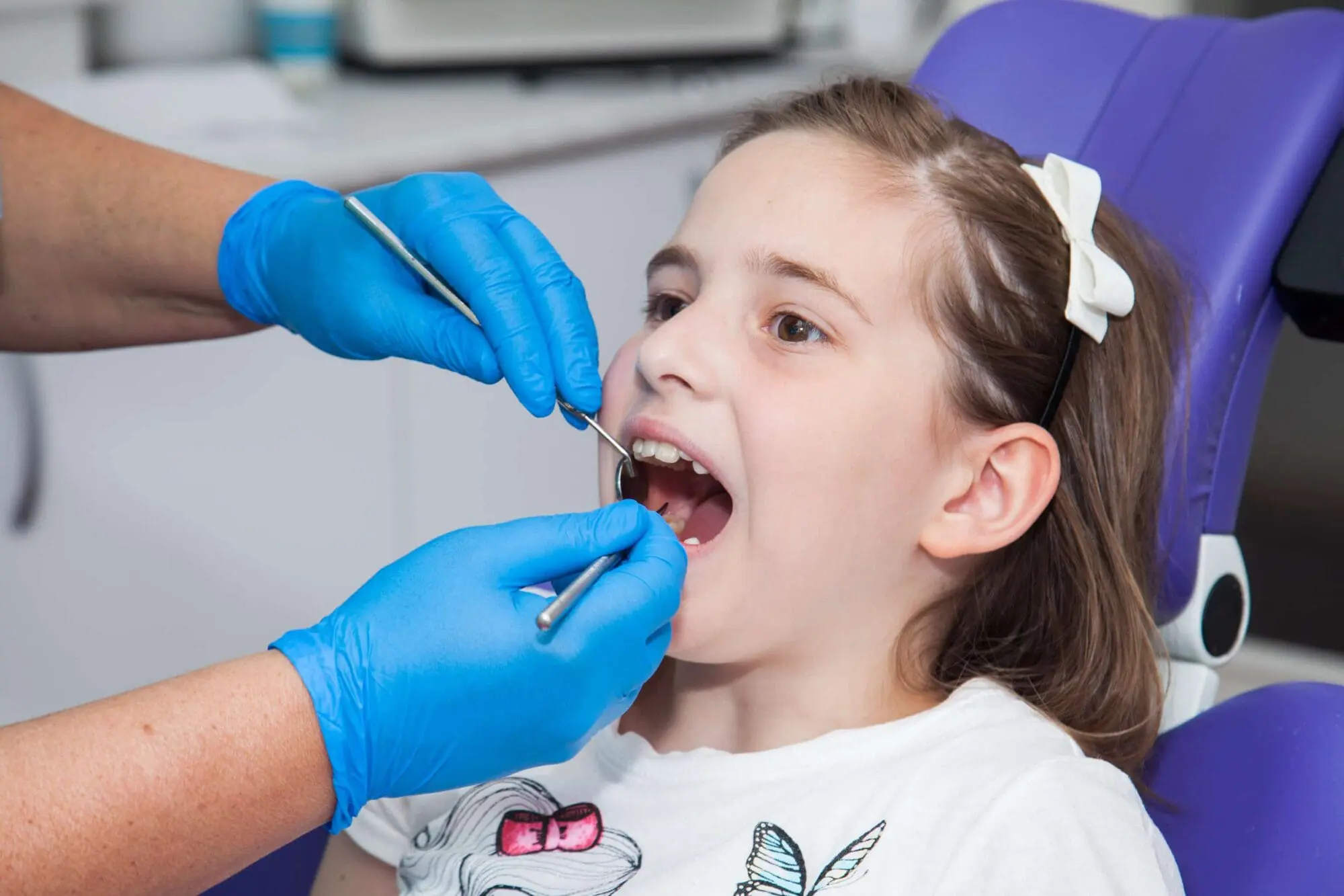 At Pediatric Dentistry and Orthodontics of Forsyth - Cumming in Cumming GA, a child comfortably sits in dental chair as the dentist uses advanced tools to perform a quick, stitch-free CO₂-laser frenectomy—examining and treating her teeth in just two minutes.