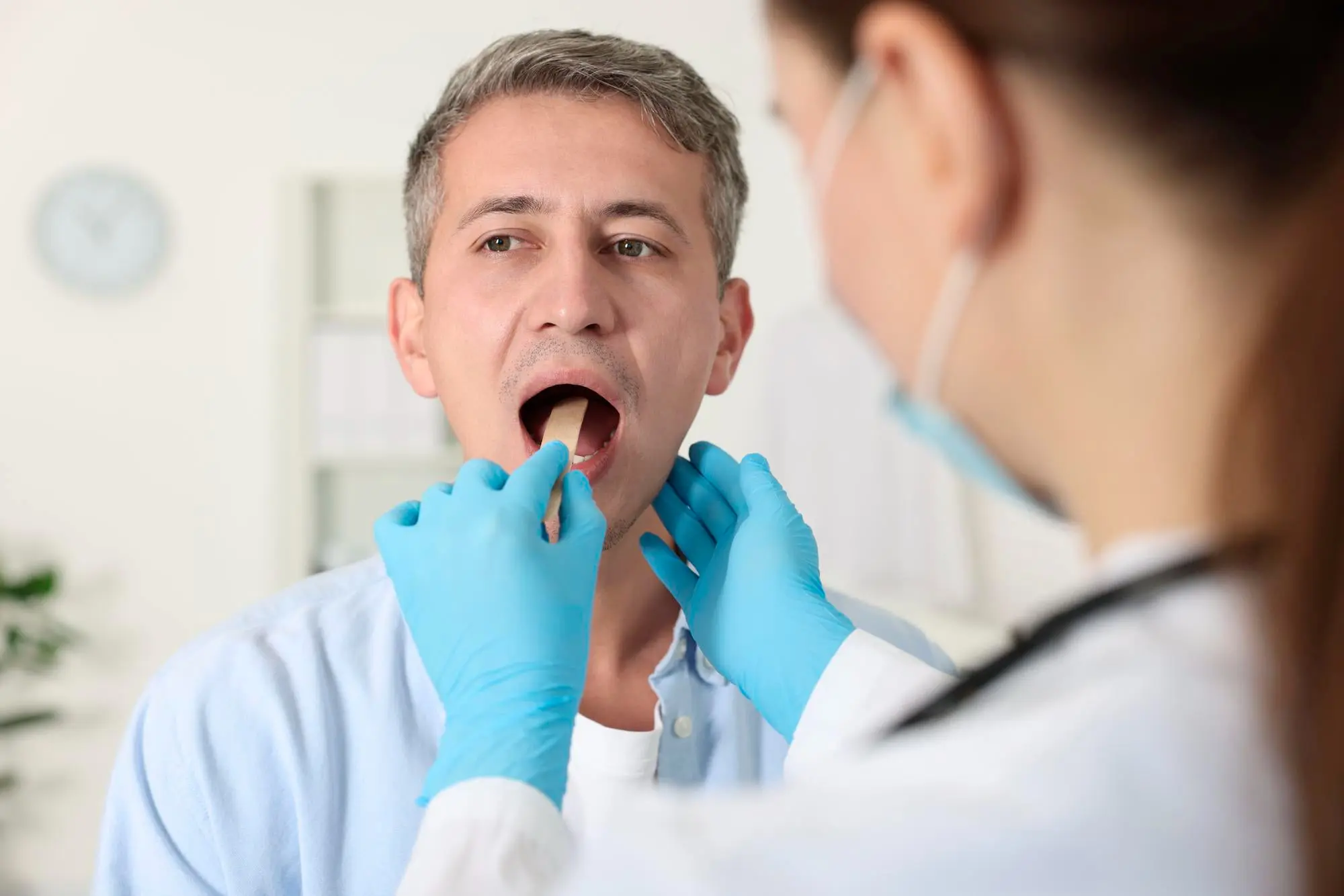 At Forsyth Pediatric Dentistry and Orthodontics in Cumming, GA, a gloved professional examines tongue thrust with a tongue depressor.
