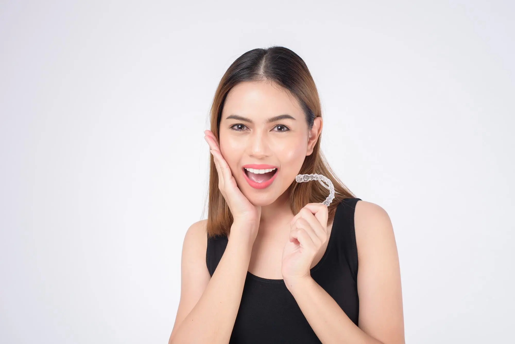 A woman holds a toothbrush in front of her face, promoting affordable Invisalign at Pediatric Dentistry and Orthodontics of Forsyth - Cumming in Cumming, GA