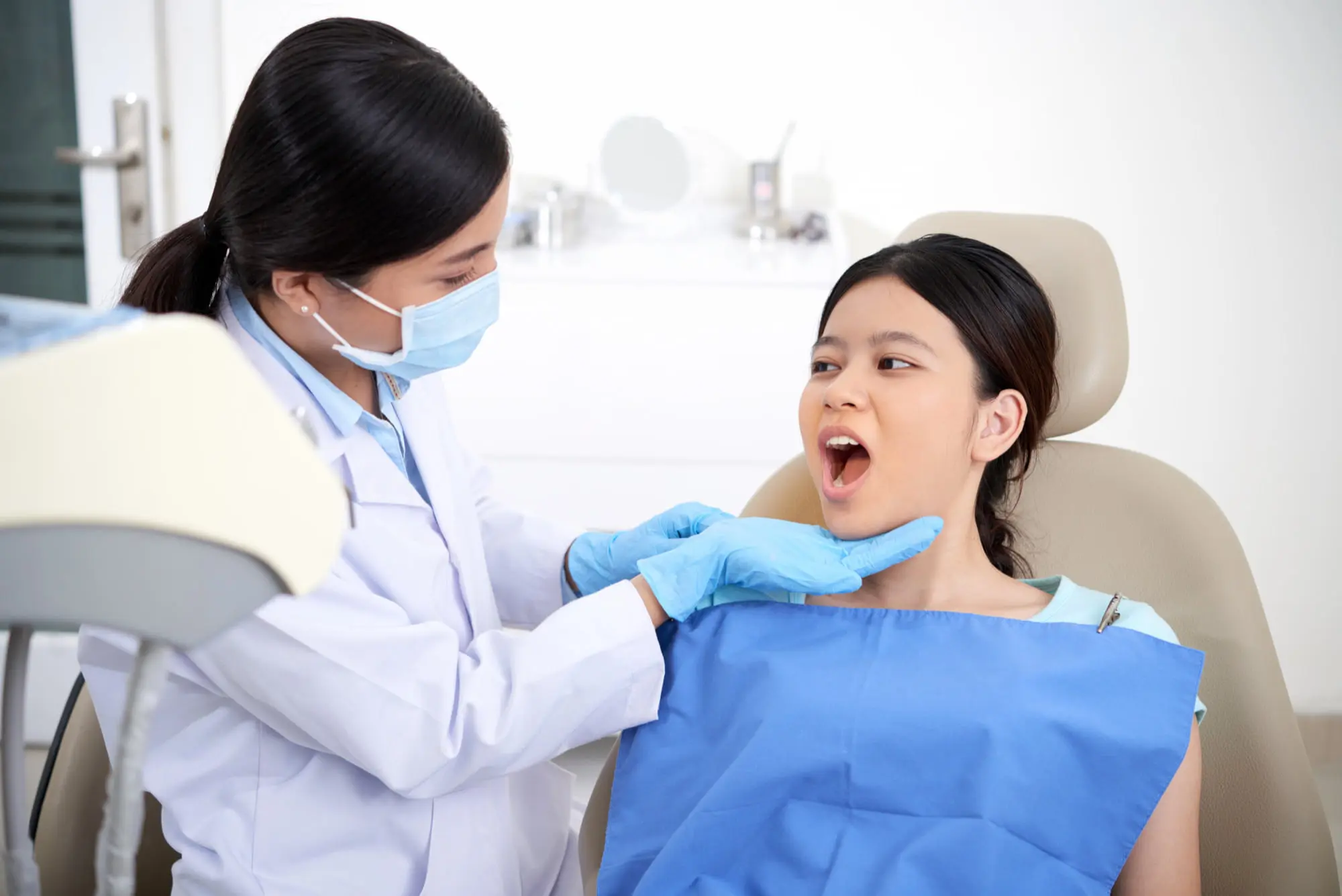 A dentist at Forsyth Pediatric Dentistry and Orthodontics in Cumming, GA examines a female patient's open mouth for plan jaw surgery.