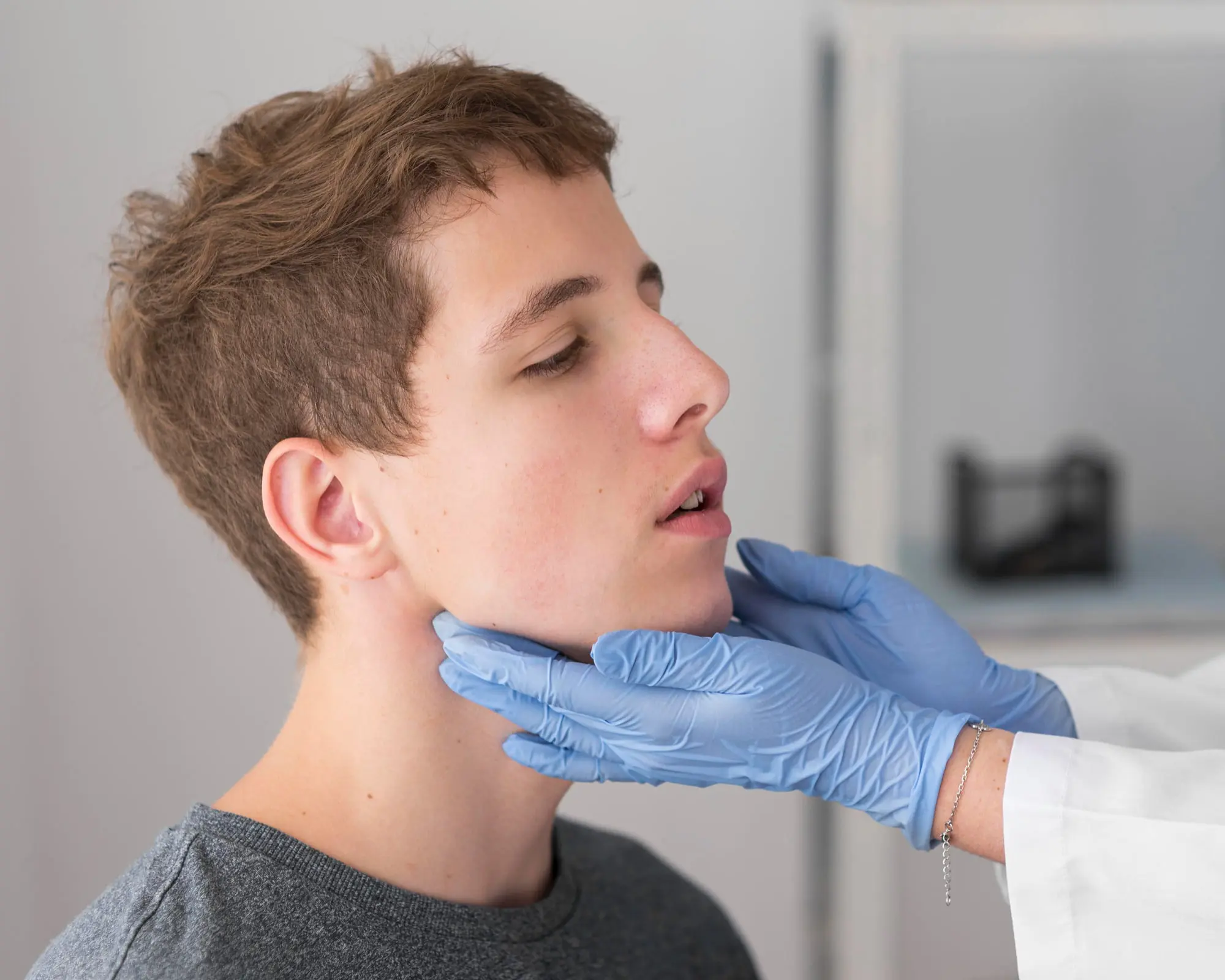 At Forsyth Pediatric Dentistry and Orthodontics in Cumming, GA, a gloved professional examines a young male's jaw surgery and neck.