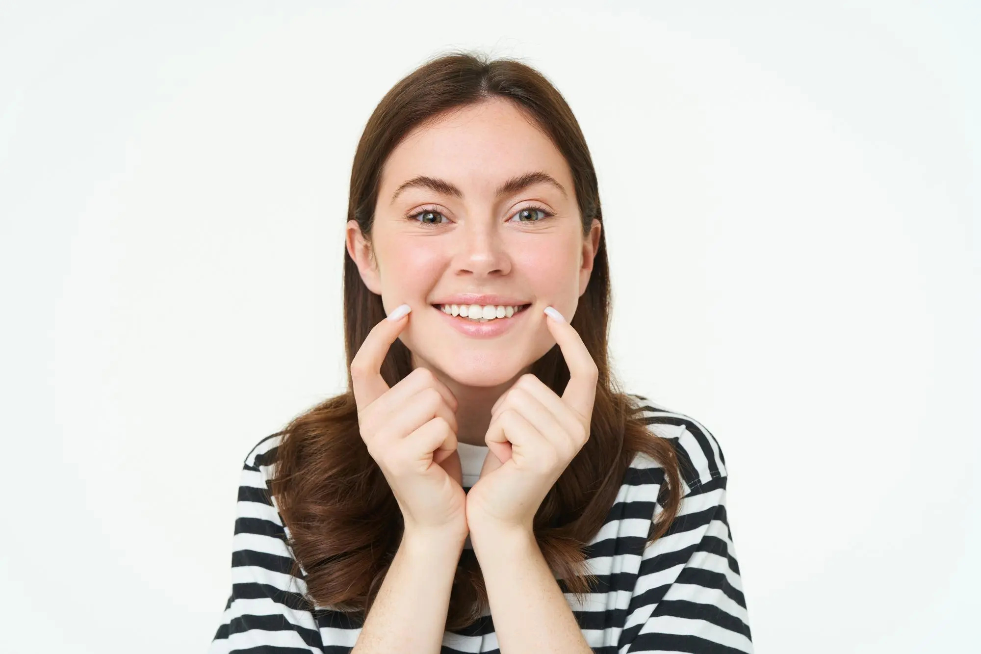 Smiling woman in striped shirt points to her teeth, plan for underbite treatment at Forsyth Pediatric Dentistry and Orthodontics in Cumming, GA.