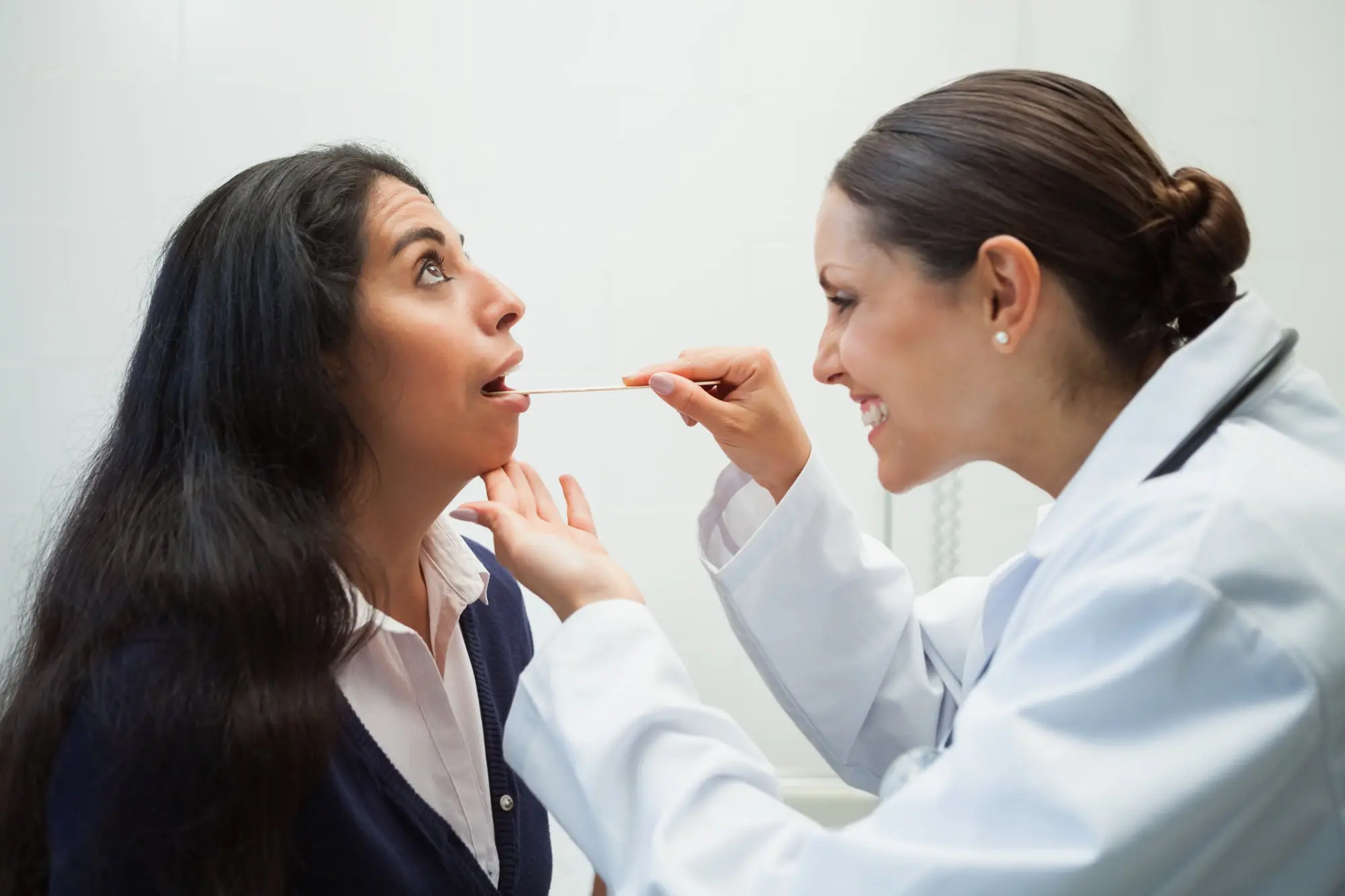 At Forsyth Pediatric Dentistry and Orthodontics in Cumming, GA, a doctor checks a woman's throat for swallowing issues or tongue thrust.