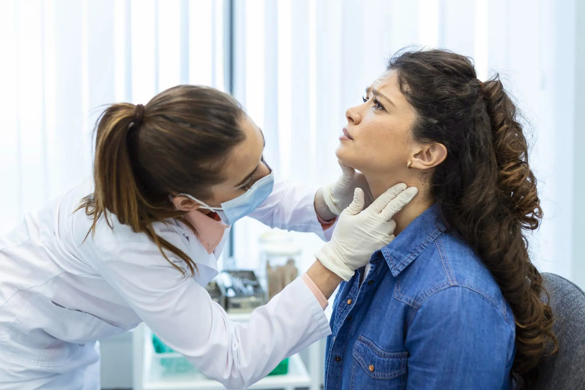 At Forsyth Pediatric Dentistry and Orthodontics in Cumming, GA, a doctor examines a concerned woman’s neck for jaw surgery.