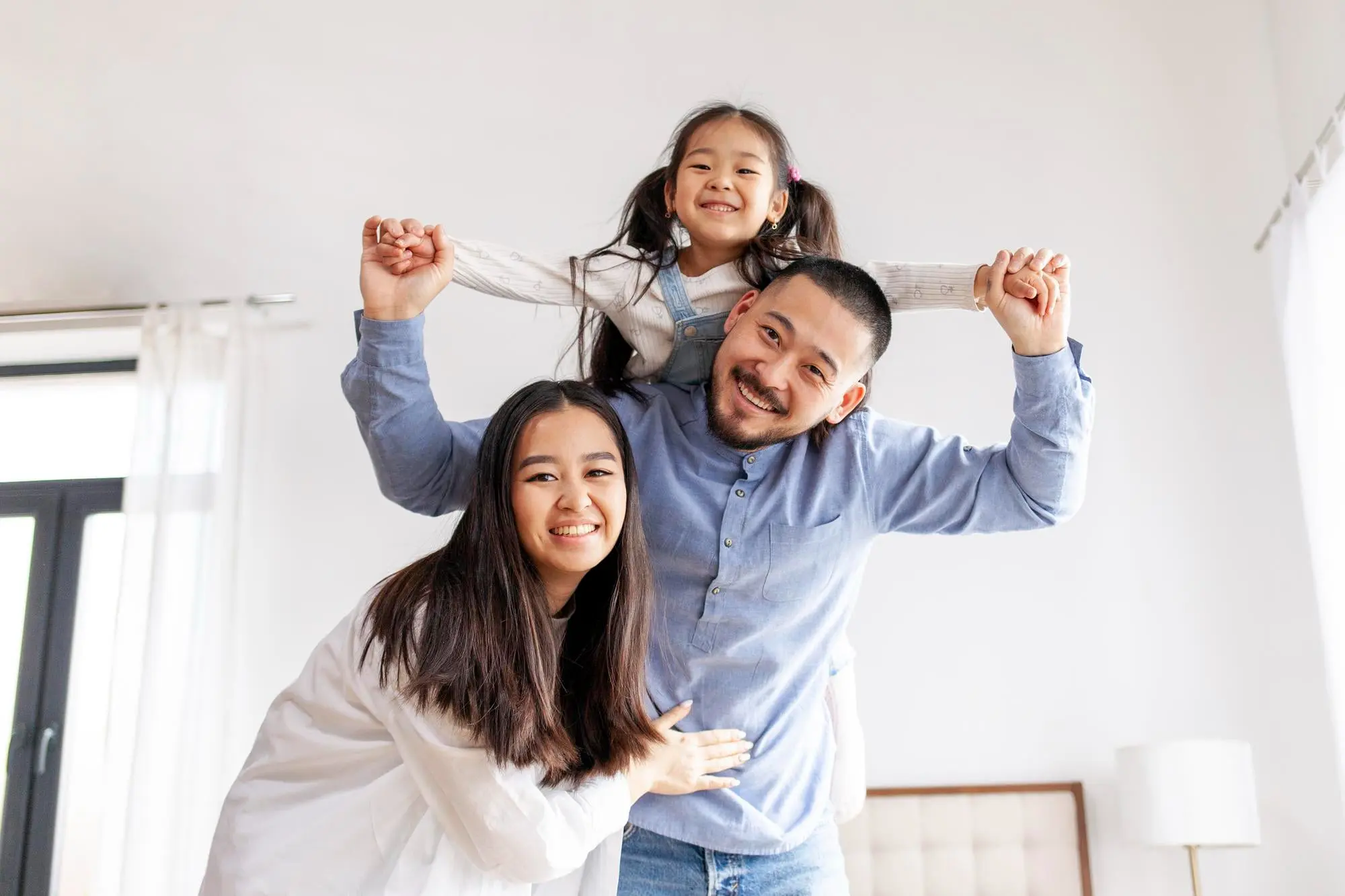 Smiling family after metal braces treatment at Pediatric Dentistry and Orthodontics of Forsyth - Cumming in Cumming, GA, in a bright room with big windows.