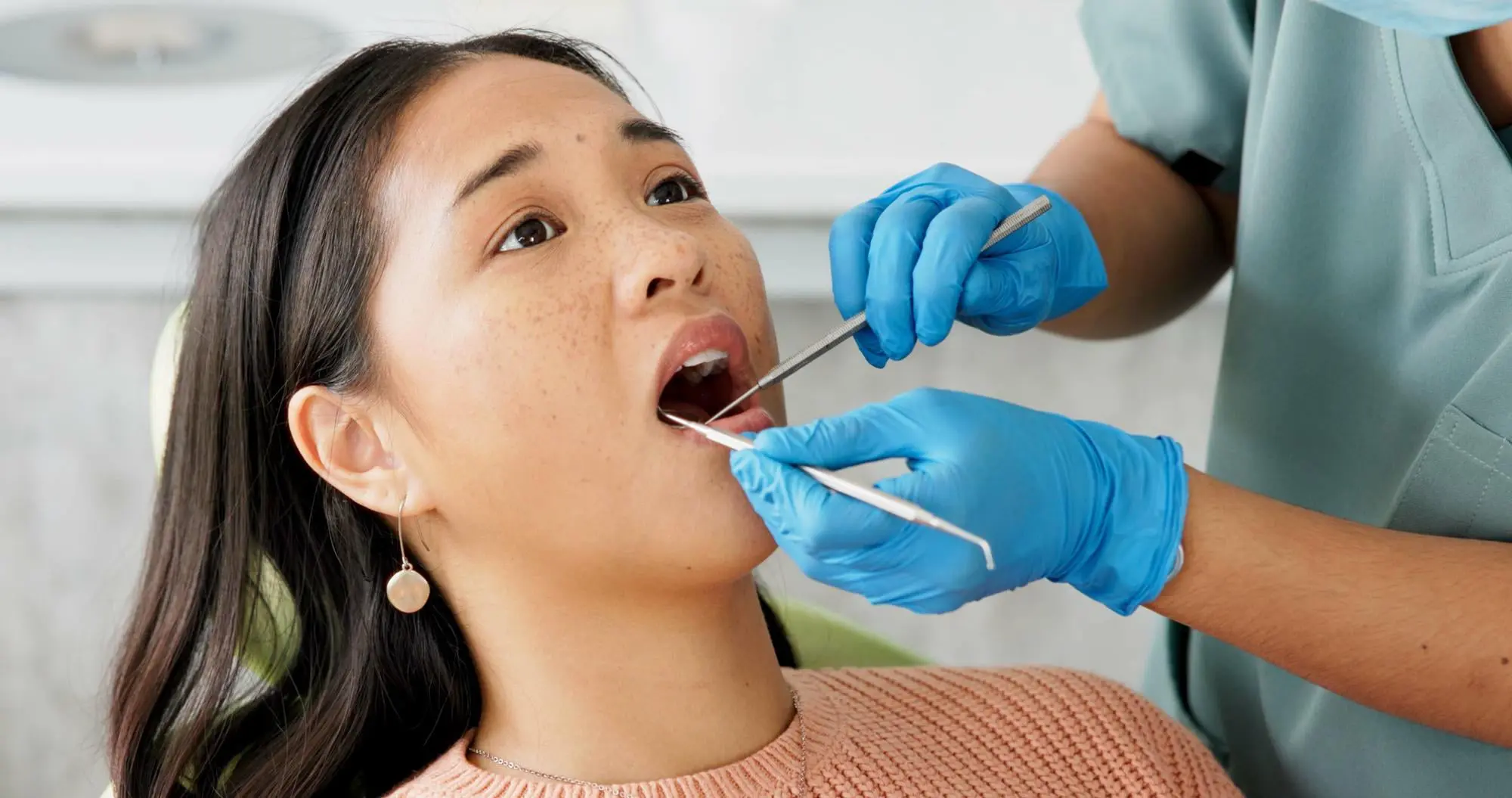 At Forsyth Pediatric Dentistry and Orthodontics in Cumming, GA, a dentist checks a woman's mouth for tongue thrust with dental tools.