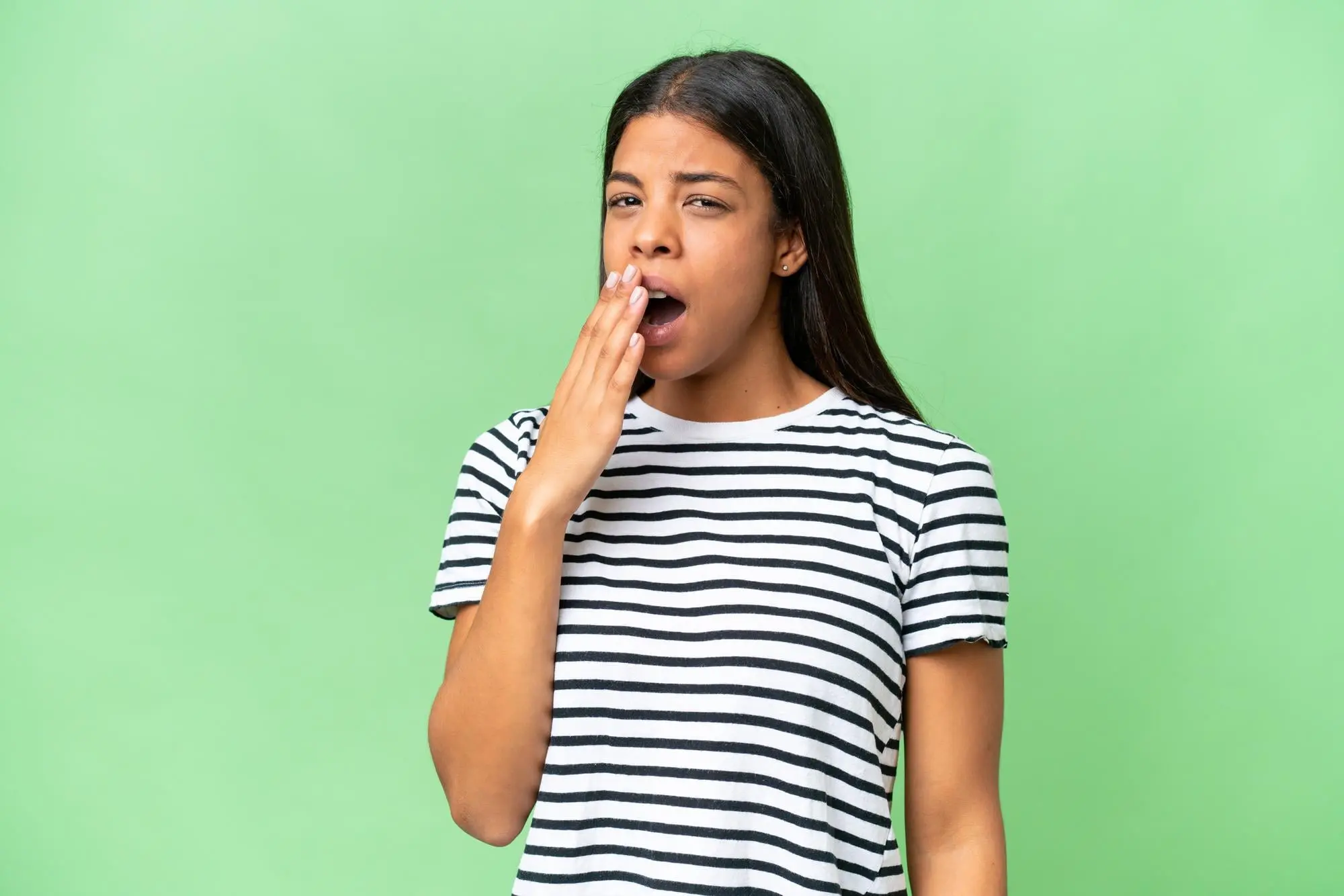 A young woman yawns with her hand over her mouth, a possible mouth breather, at Forsyth Pediatric Dentistry and Orthodontics in Cumming, GA.