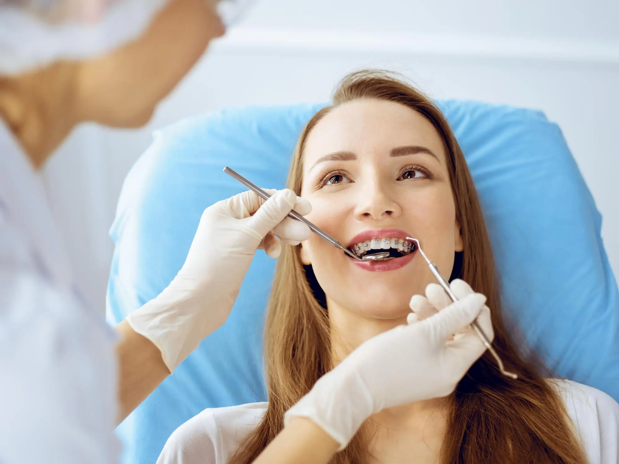 A dentist at Forsyth Pediatric Dentistry and Orthodontics in Cumming, GA examines a young woman with braces in a dental chair for fix overbite.