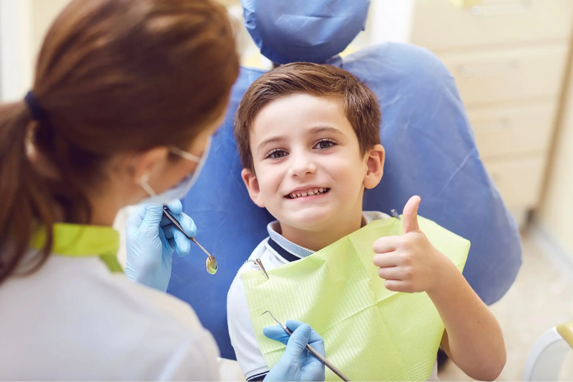 At Forsyth Pediatric Dentistry and Orthodontics in Cumming, GA, a smiling boy in a dental chair gives a thumbs up to his dentist for tongue thrust treatment.