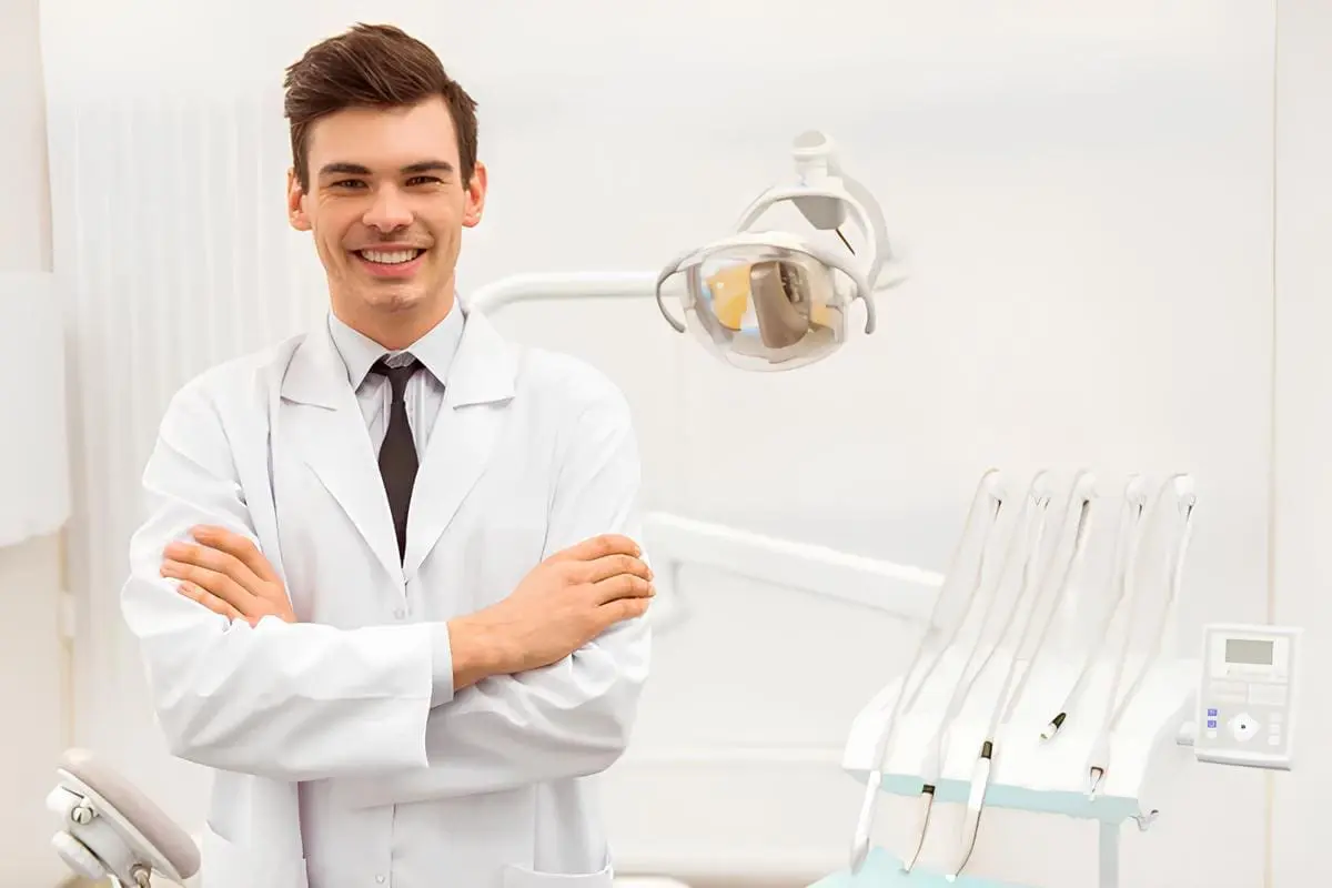At Forsyth Pediatric Dentistry and Orthodontics in Cumming, GA, a dentist stands with arms crossed amid dental equipment and chair for jaw surgery.
