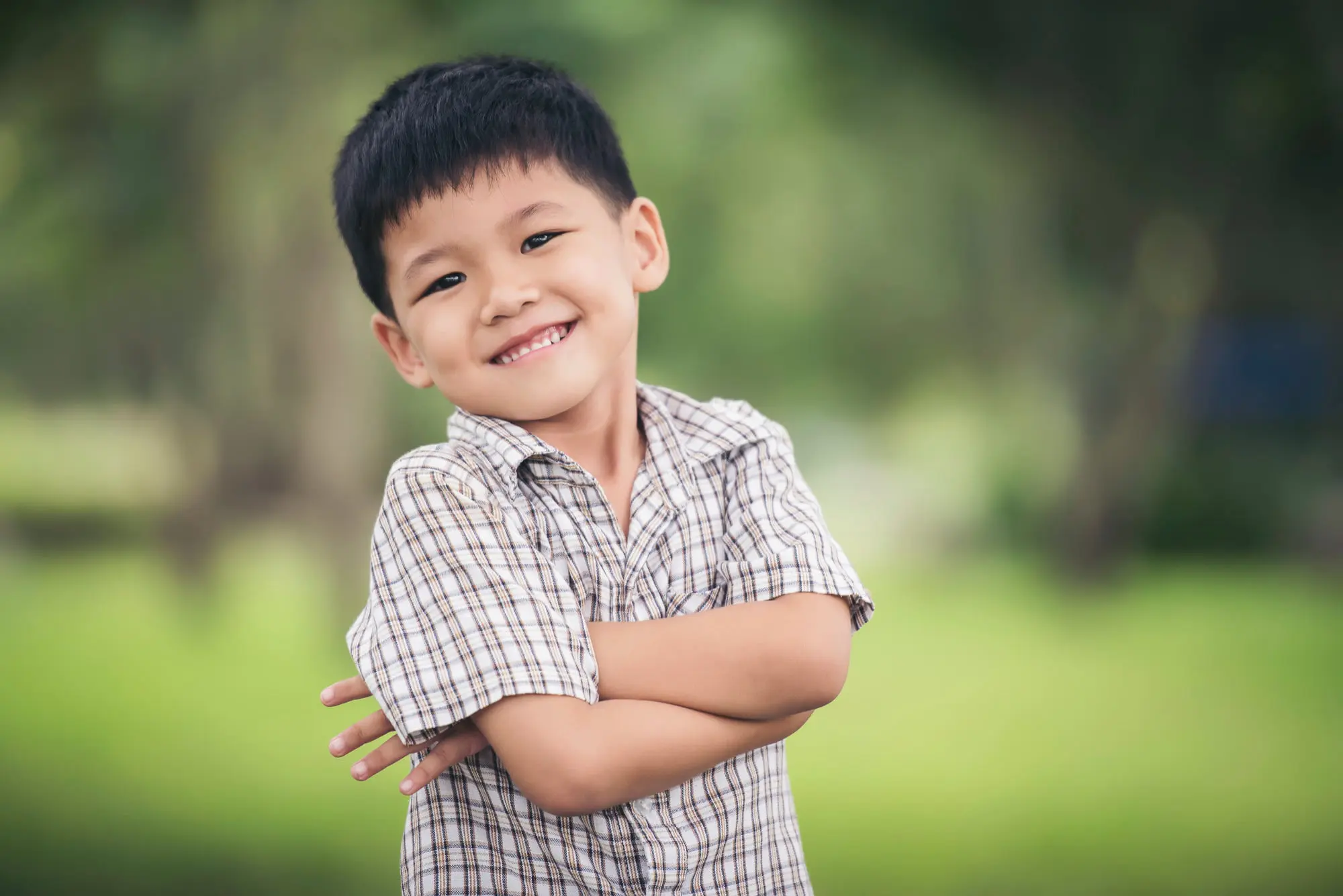 A smiling young boy stands in a park, embodying happiness and the benefits of restorative dentistry for children in Cumming, GA