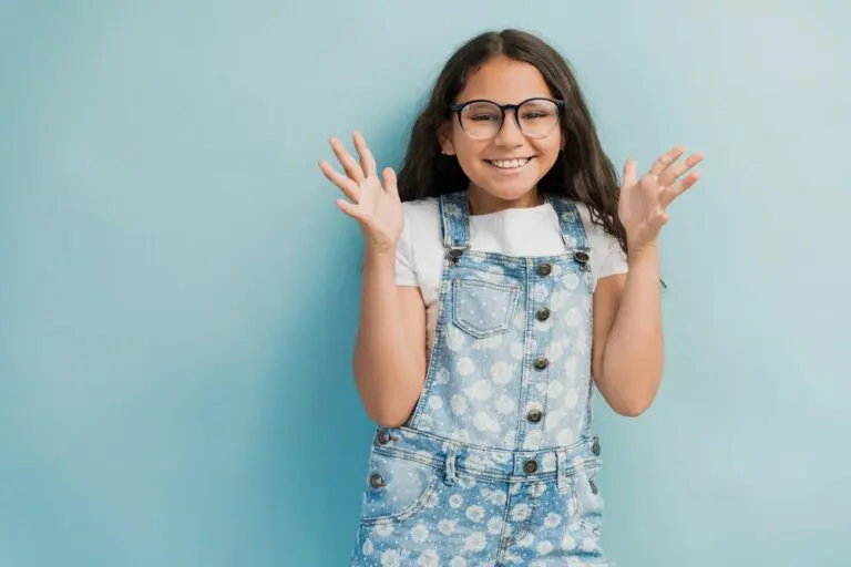 A smiling girl with long brown hair and glasses poses playfully, perfect for Forsyth Pediatric Dentistry and Orthodontics in Cumming, GA - Best Toothbrush for Kids by Age – Cumming Parent Guide