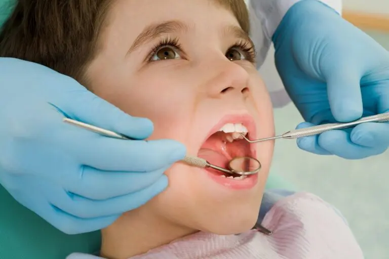 A child has their teeth examined with dental tools by a blue-gloved professional at Forsyth Pediatric Dentistry and Orthodontics in Cumming, GA.