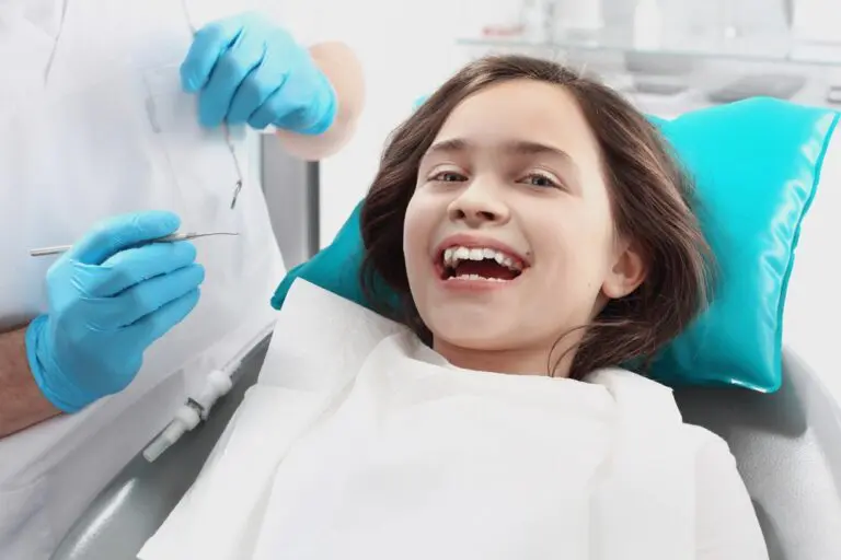 A smiling girl in a dental chair with a blue headrest and dentist nearby at Forsyth Pediatric Dentistry and Orthodontics in Cumming, GA - Tooth-Friendly Snacks for Kids: Dentist Recommendations from Cumming, GA